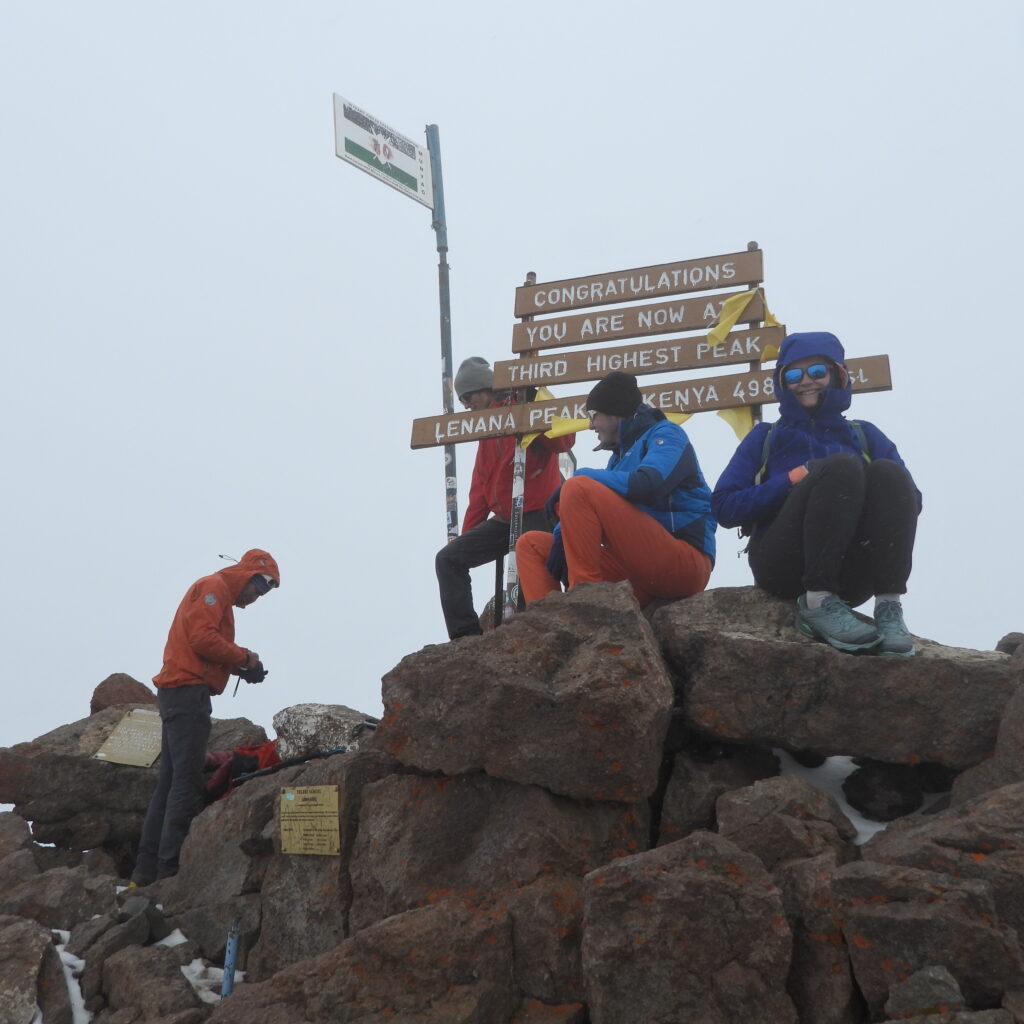 Trekkers at the Point Lenana summit sign, the third-highest peak on Mount Kenya at 4,985 meter