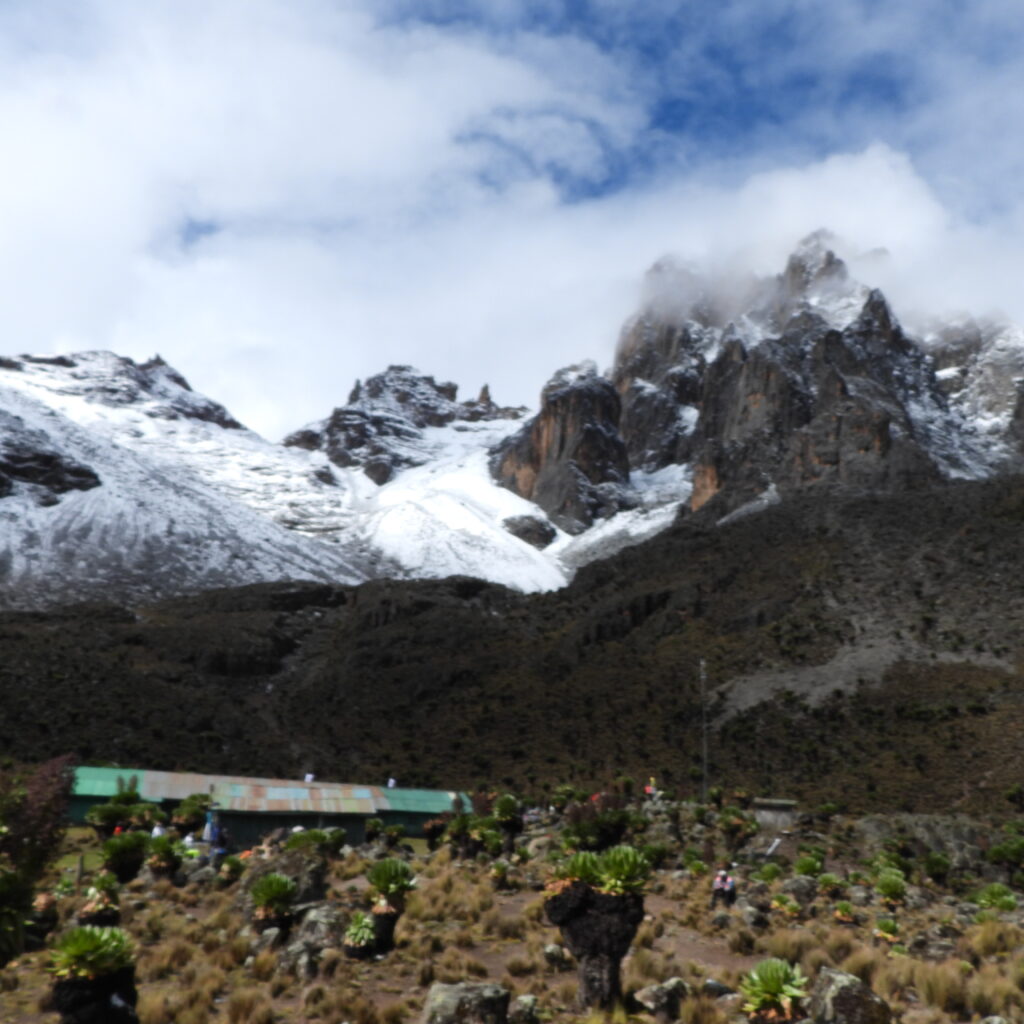 Snow-covered Batian and Nelion peaks towering over Shipton’s Camp on Mount Kenya’s