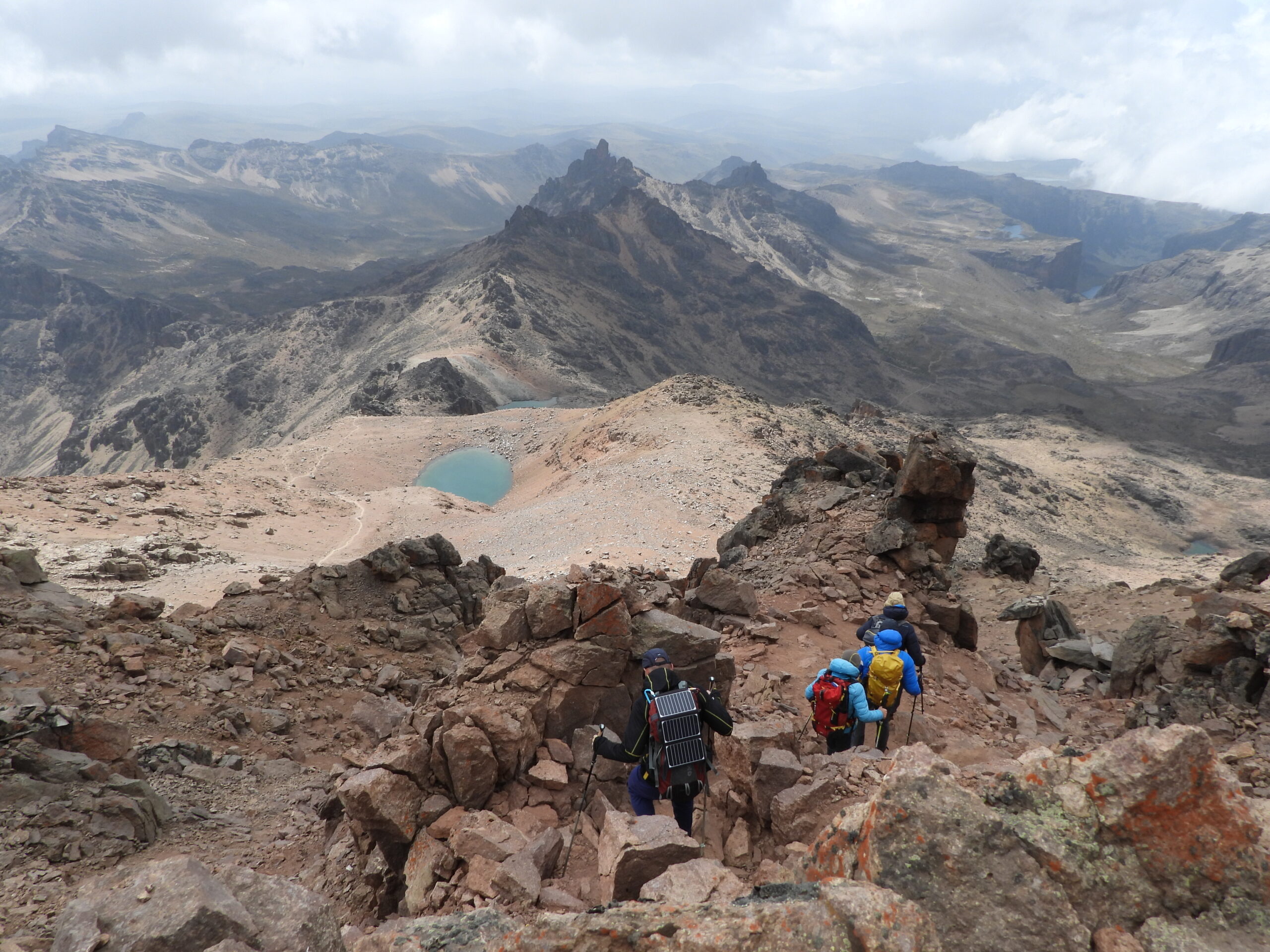 Trekkers descending from Point Lenana on Mount Kenya with views of alpine tarns and Gorges Valle Trekkers descending from Point Lenana on Mount Kenya with views of alpine tarns and Gorges Valle